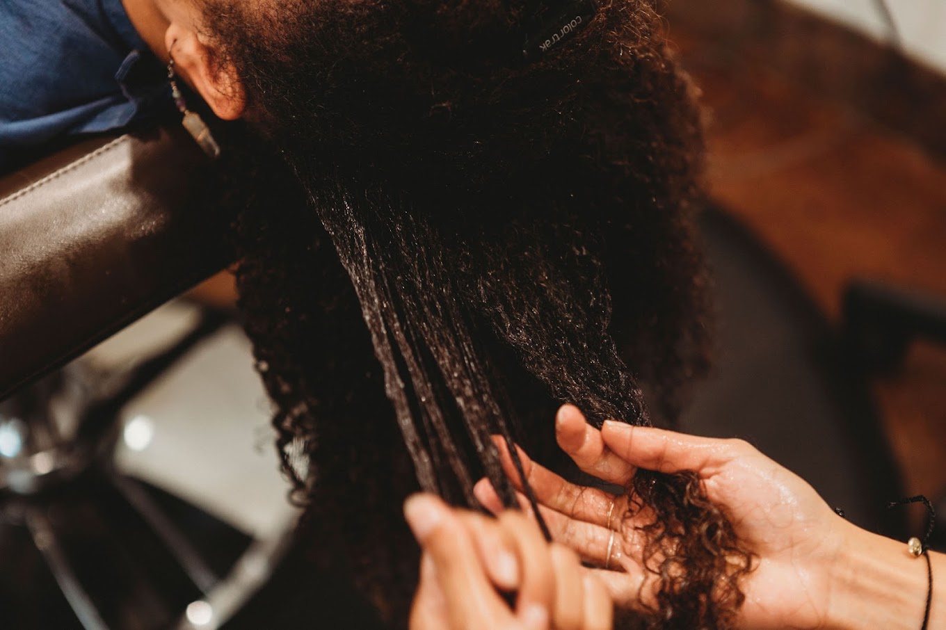 Close-up of hands working product through long, wet curly hair
